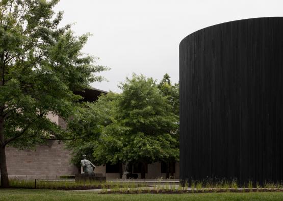 a black cylinder with a statue in the background