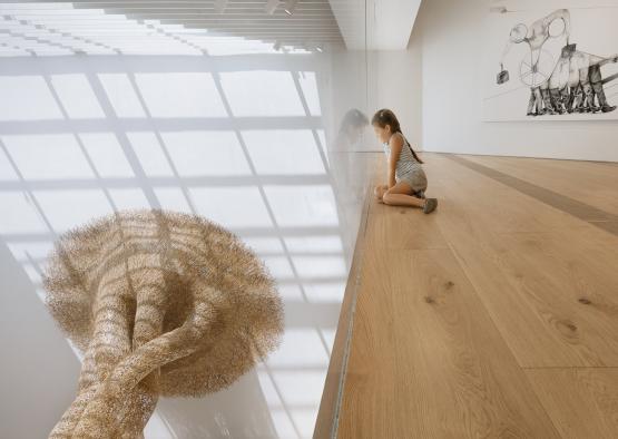 a girl sitting on a wood floor looking at a tree made of dots