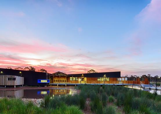 a building with a body of water and a pond with a pink and blue sky