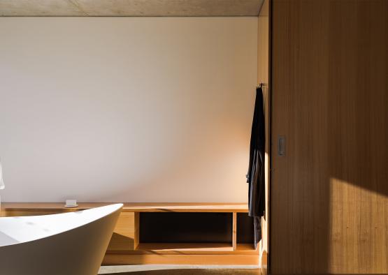 a bathroom with a white bathtub and a wooden shelf