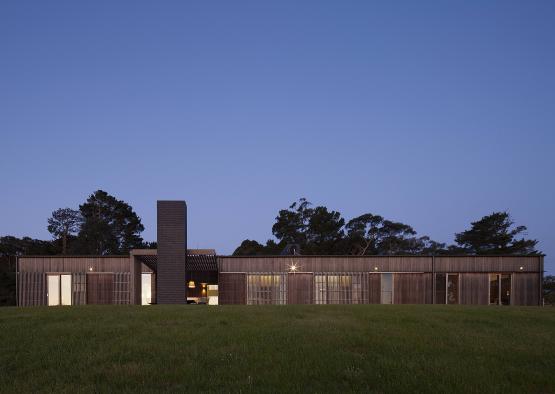 a building with a chimney in front of a grassy field