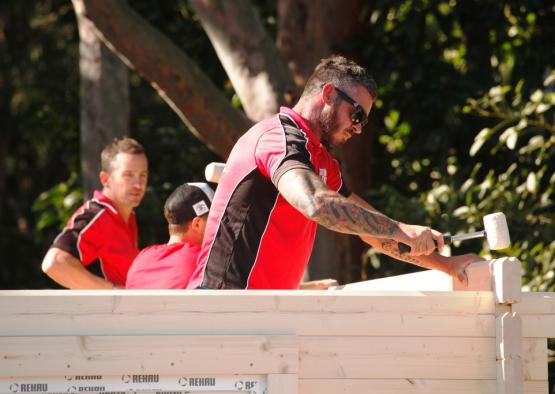 a man in red shirt holding hammer and wood