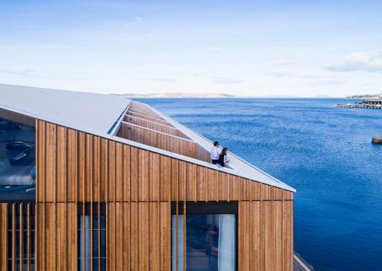 a couple sitting on a roof overlooking a body of water