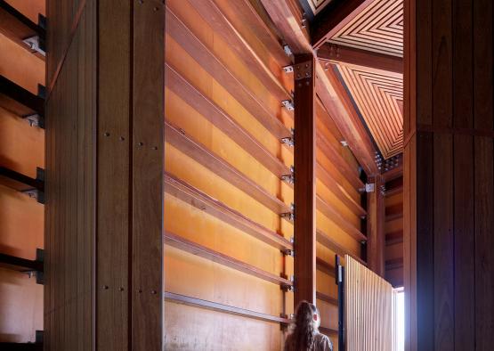 a woman standing in a room with a wooden wall