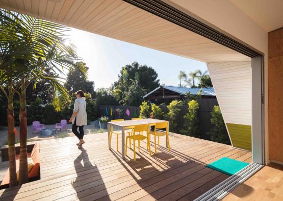 a woman walking on a deck with a table and chairs