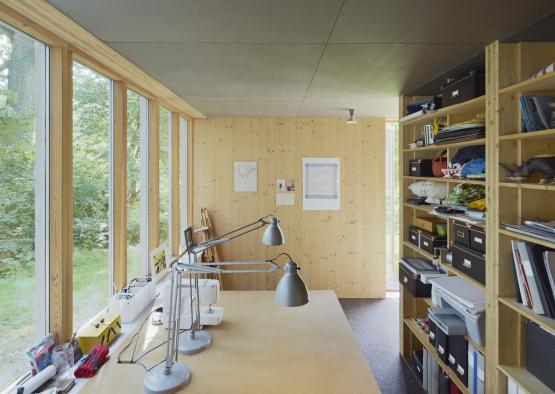 a desk with a lamp and shelves in a room with windows