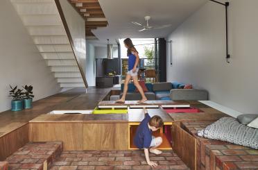 a boy and girl walking on a platform in a room with stairs