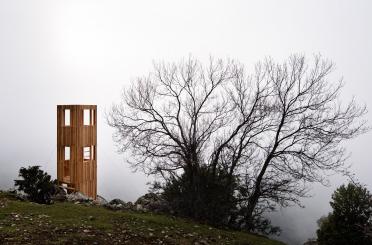 a wooden structure on a hill with trees in the background