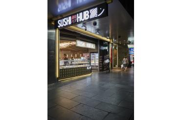 a storefront with a sign and people walking in the background